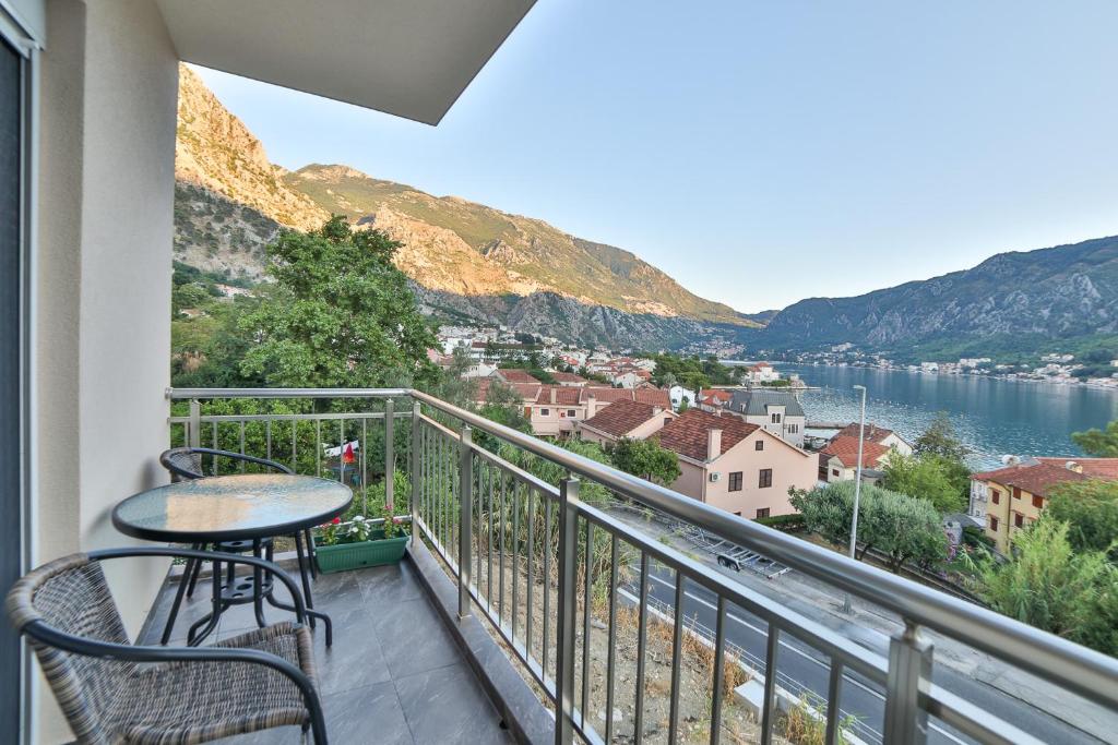 einen Balkon mit einem Tisch und Stühlen sowie Blick auf das Wasser in der Unterkunft Java Apartments in Dobrota