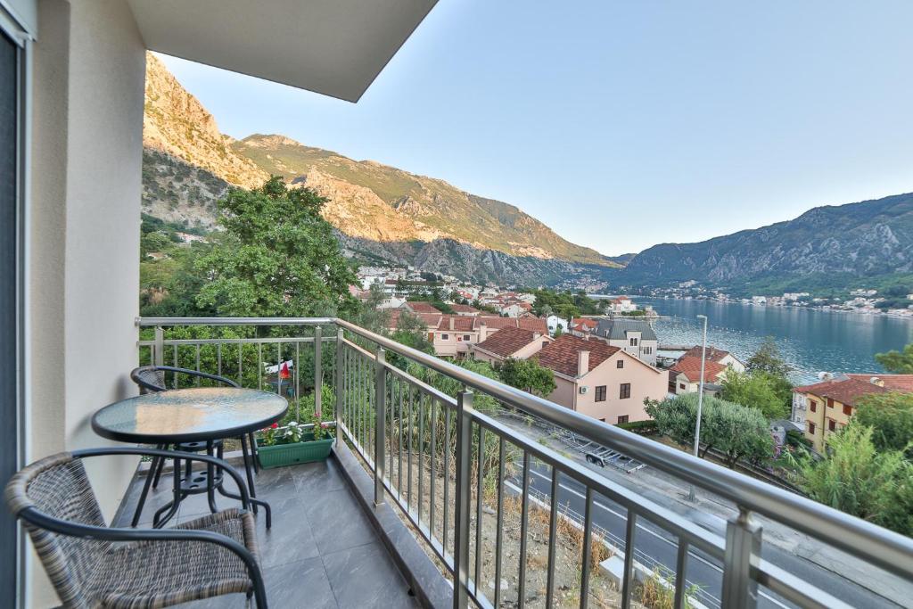 een balkon met een tafel en stoelen en uitzicht op het water bij Java Apartments in Dobrota