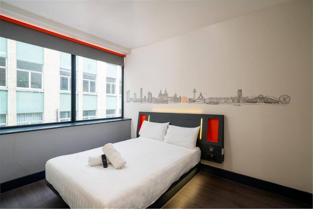 1 dormitorio con 1 cama con sábanas blancas y ventana en easyHotel Liverpool, en Liverpool