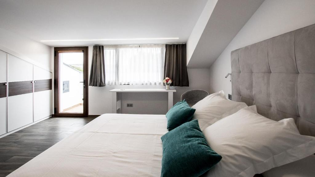 a bedroom with a large white bed with green pillows at Hotel Duque de Calabria in Manzanera