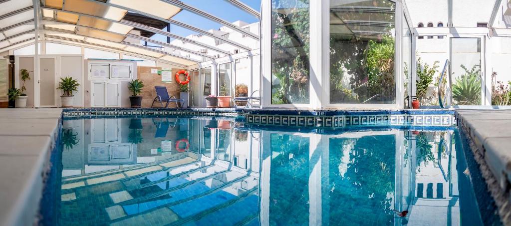 a swimming pool in a house with a glass wall at Hotel Senderos in Agua Amarga