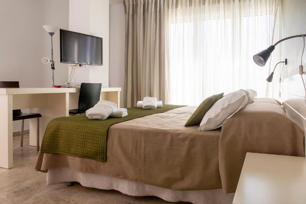 a hotel room with a bed and a desk and a window at Hotel Senderos in Agua Amarga