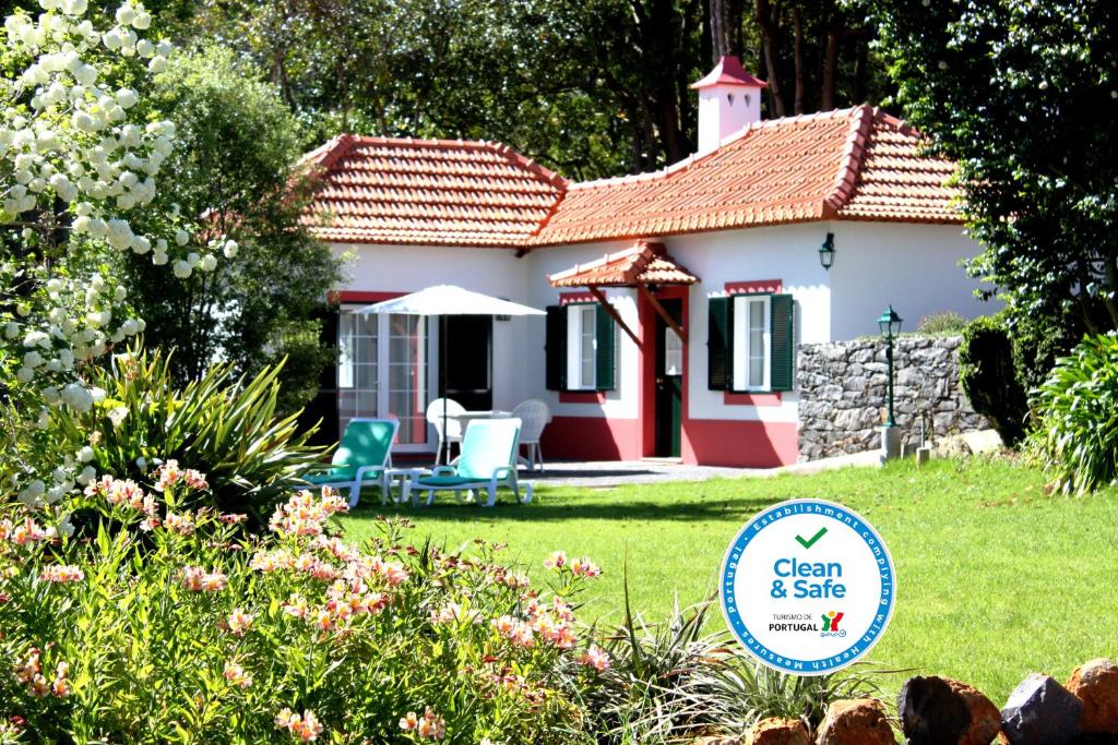 une petite maison rouge et blanche avec une cour dans l'établissement Quinta Das Faias, à Camacha