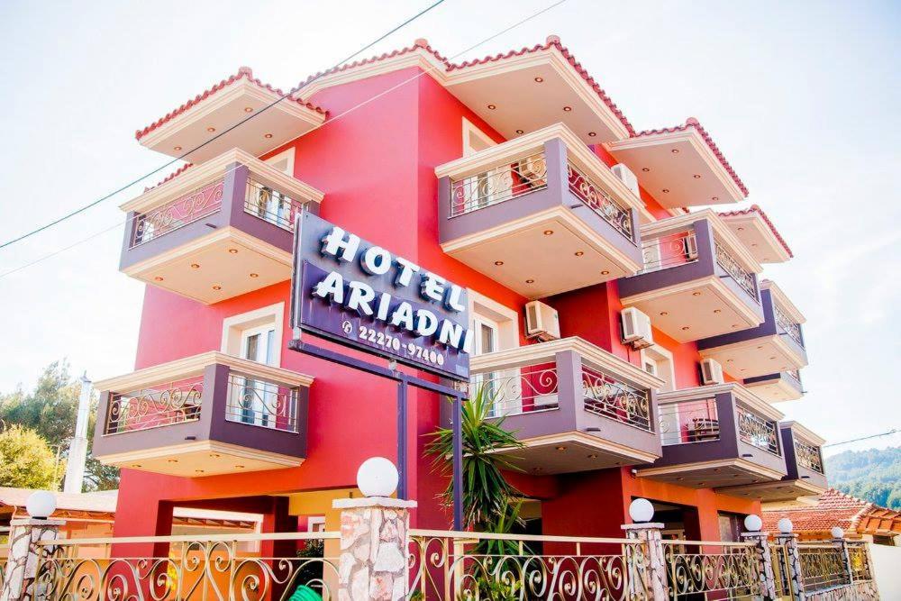 a red building with balconies and a sign on it at HOTEL ARIADNI in Ayia anna