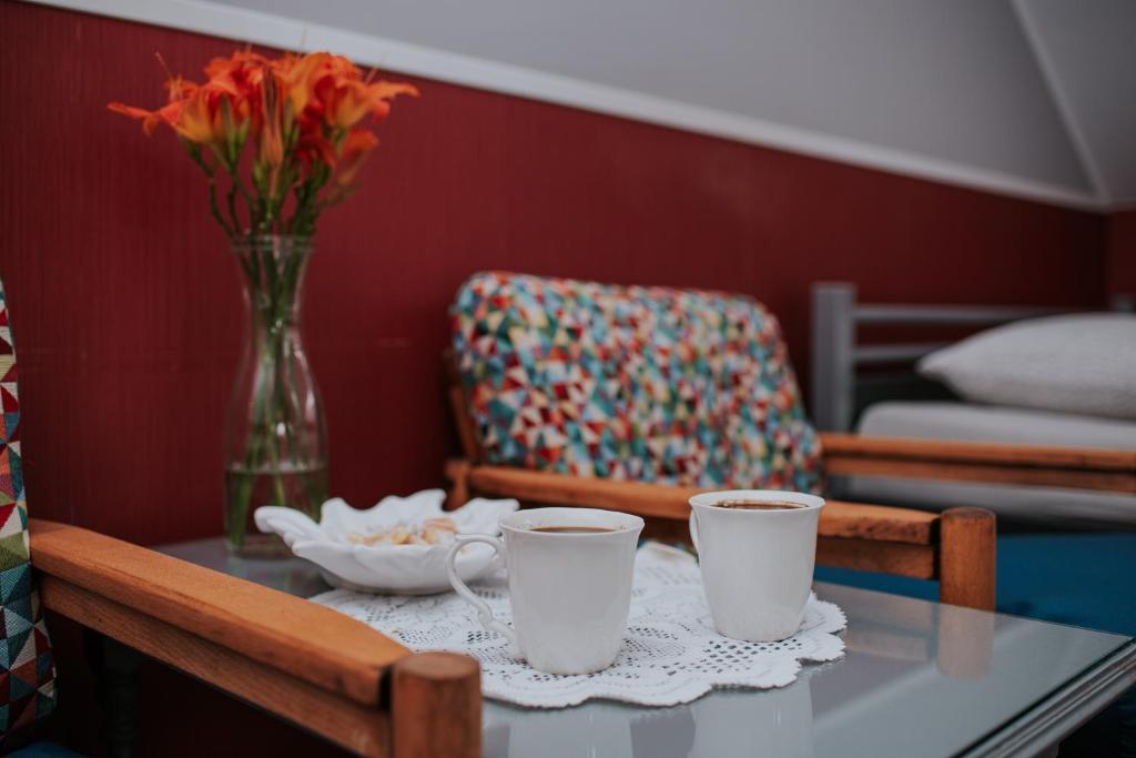 una mesa con dos tazas de café y un jarrón con flores en Agroturystyka Małgosia en Lubiąż