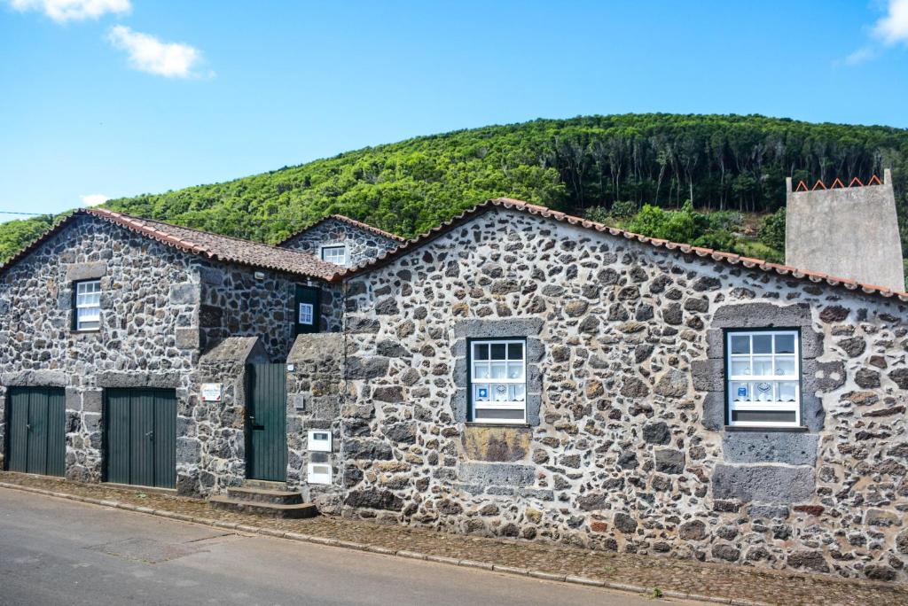 a stone house with a hill in the background at Quinta dos Frutos in Santa Cruz da Graciosa