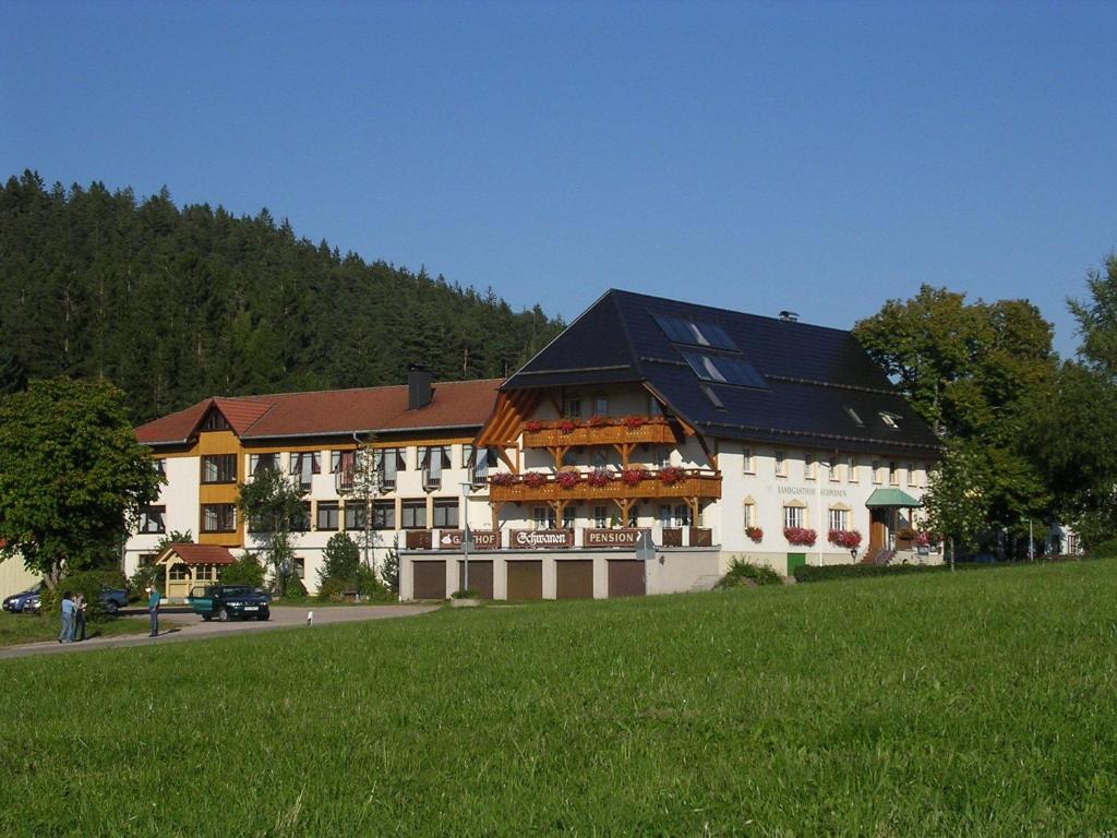 ein großes weißes Gebäude mit schwarzem Dach in der Unterkunft Landgasthof Zum Schwanen in Hornberg