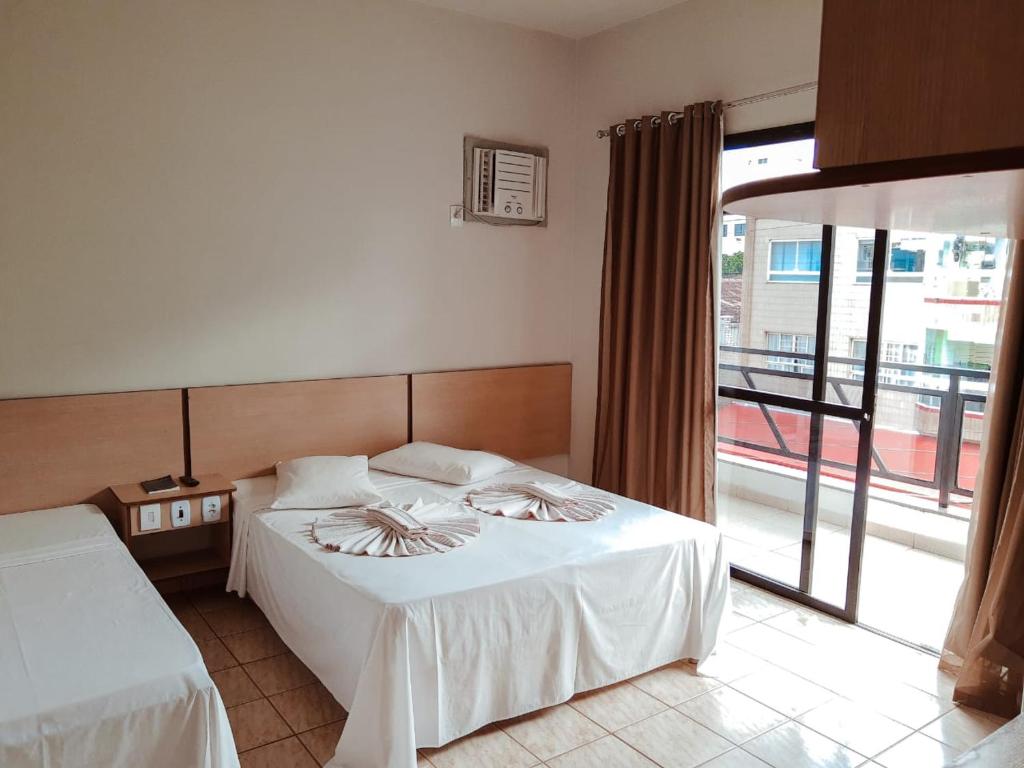 a hotel room with two beds and a balcony at Pousada Solar Meaipe in Meaípe