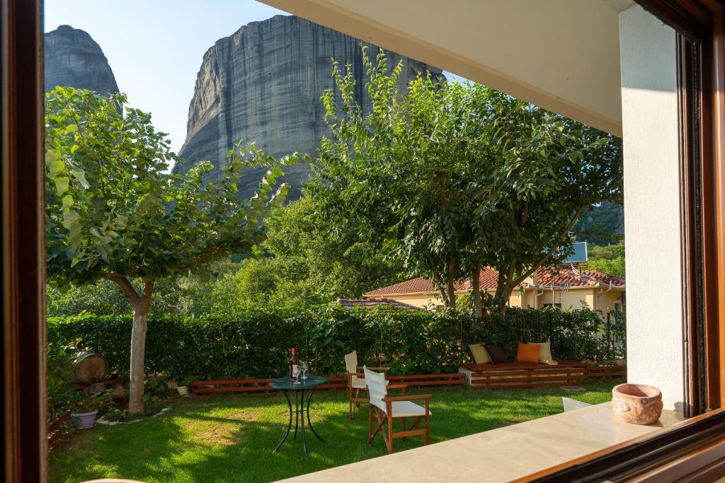 uma janela com vista para um jardim com uma mesa e cadeiras em Meteora Nature em Kalabaka