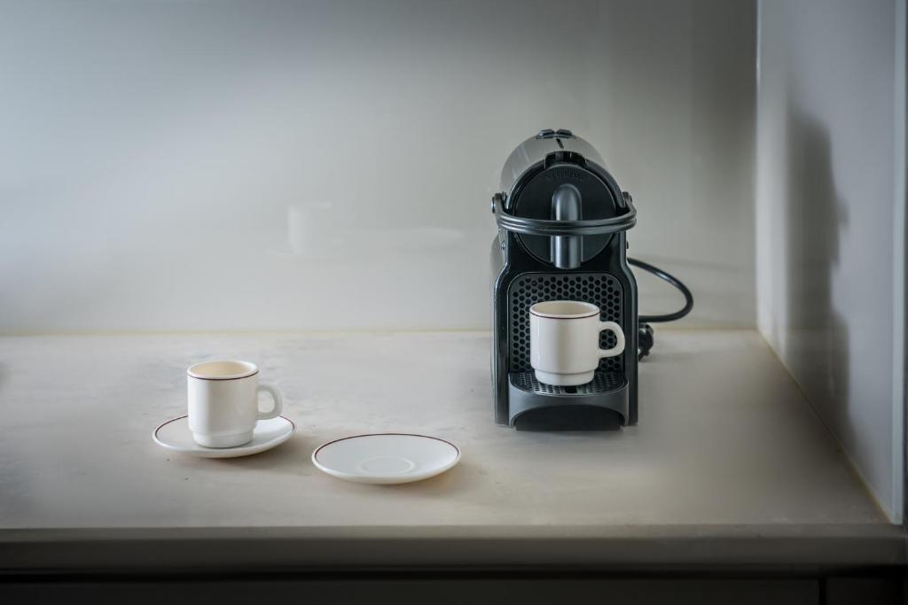 two cups of coffee sitting on a counter with a tea kettle at Skajado Holiday Apartments in Stalís