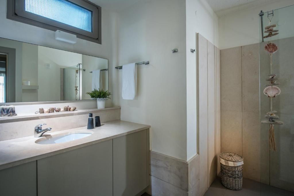 a bathroom with a sink and a mirror and a shower at Skajado Holiday Apartments in Stalís