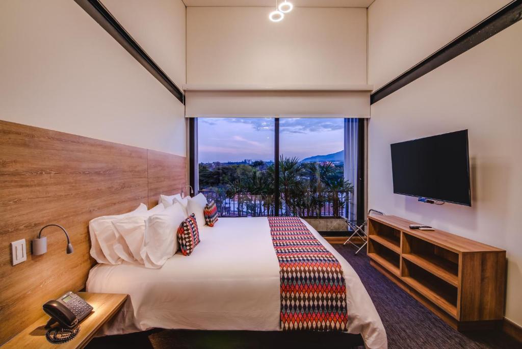 a hotel room with a large bed and a large window at Alko Hotel Integrado in Cali