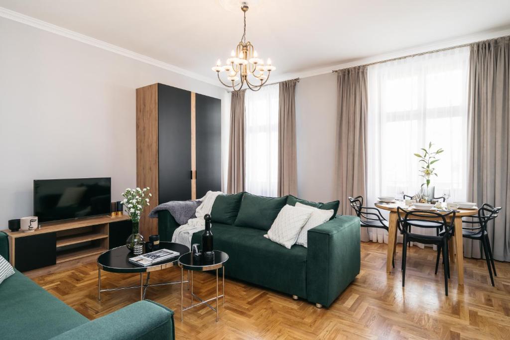 ein Wohnzimmer mit einem grünen Sofa und einem Tisch in der Unterkunft Papillon Apartment by LoftAffair in Krakau