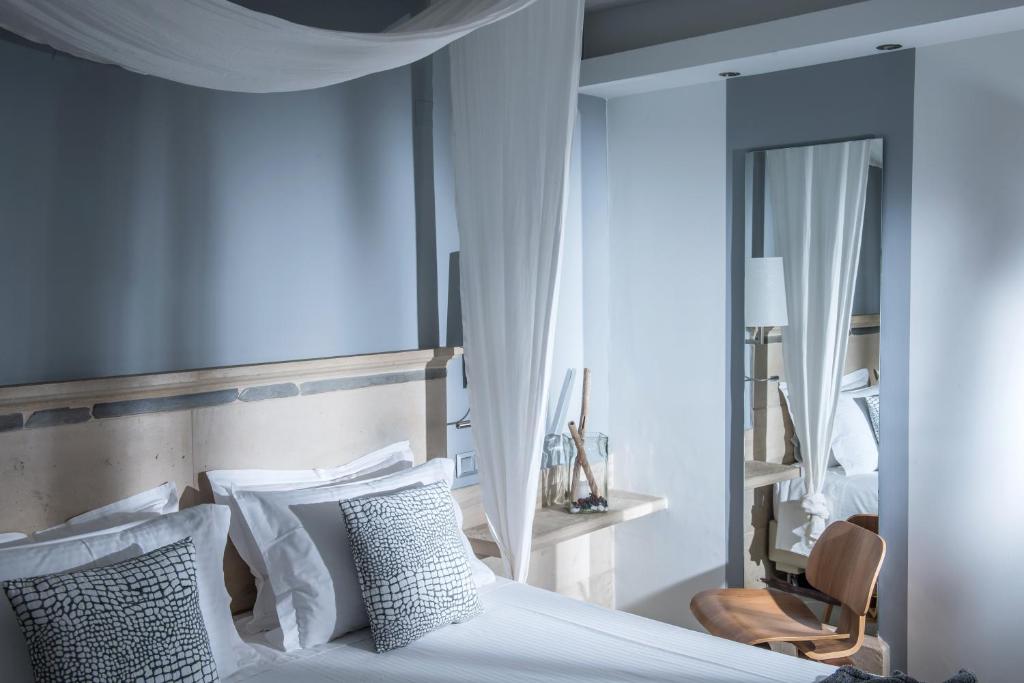 a bedroom with a bed with white pillows and a mirror at Skajado Holiday Apartments in Stalís