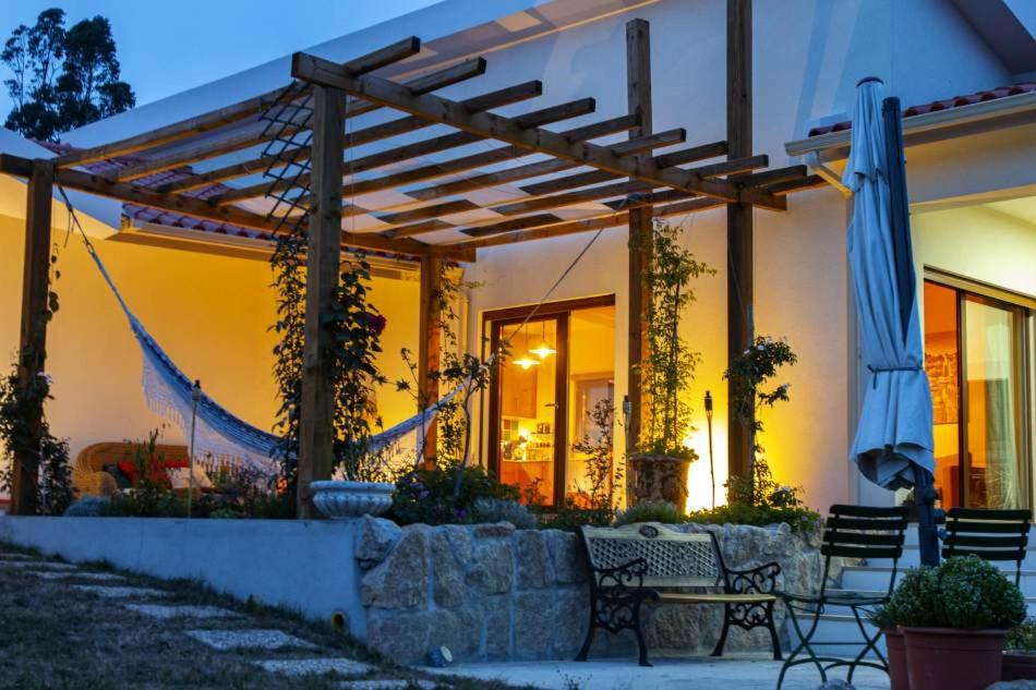 a house with a patio with chairs and an umbrella at Casa Limonina in Louriçal