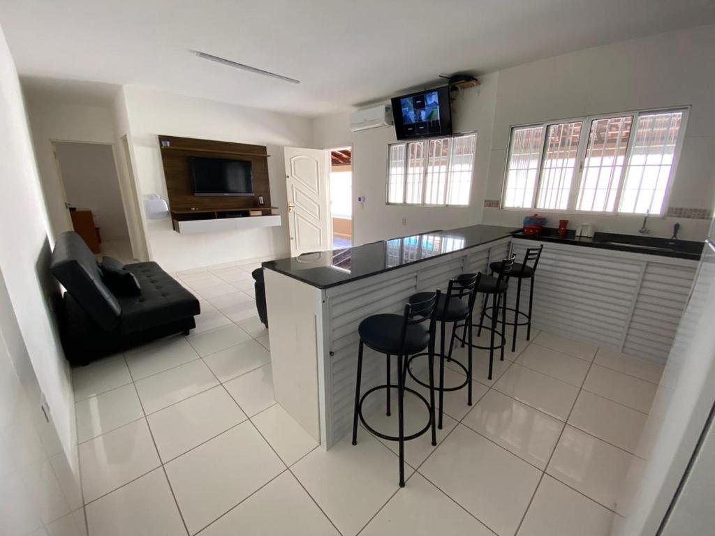 uma cozinha com um balcão e bancos num quarto em AR Condicionado, Wi-FI, SEM Mofo ! em Ilha Comprida