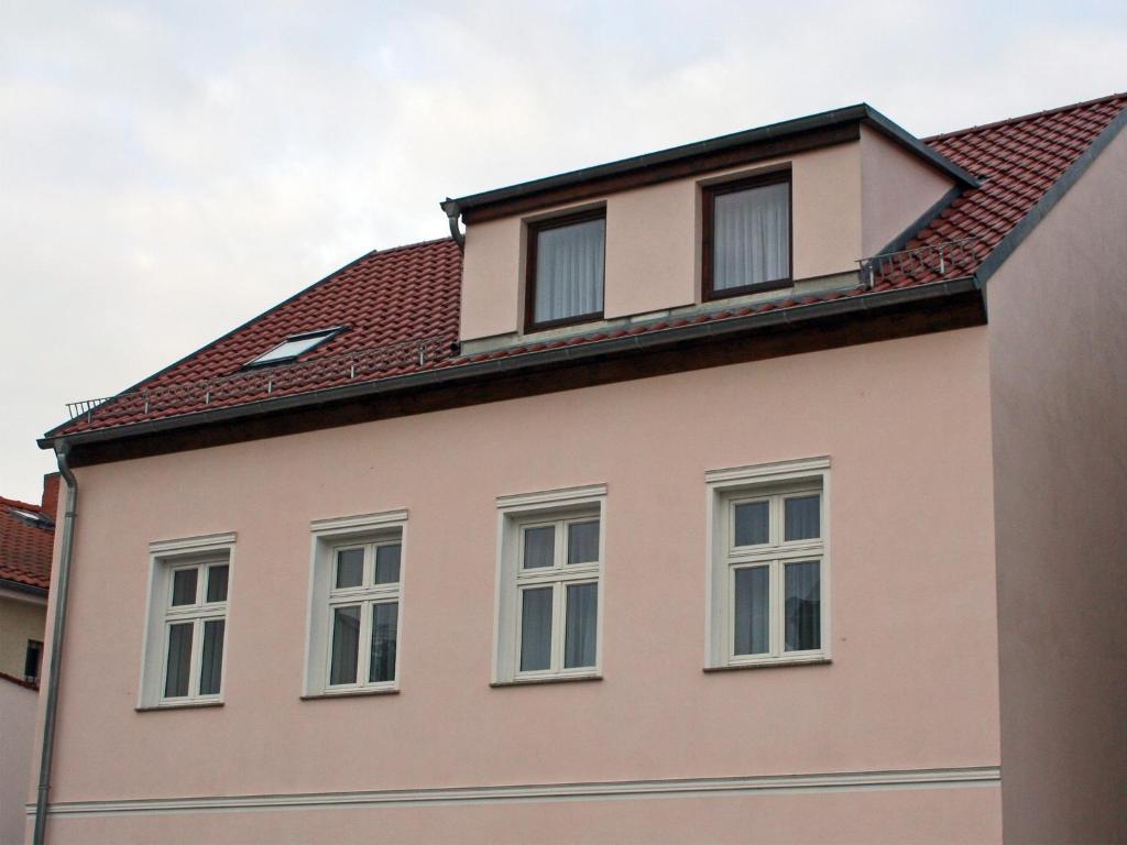 ein Haus mit weißen Fenstern und einem roten Dach in der Unterkunft Ferienwohnung Teltow in Teltow