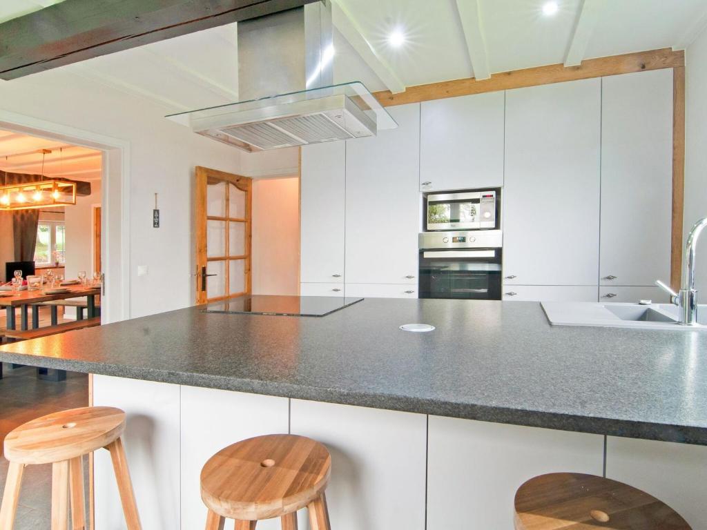 a kitchen with white cabinets and a counter with stools at Holiday Home between Spa and Eifel Nature Park in Xhoffraix