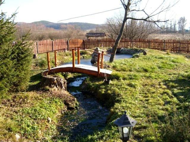 a wooden bridge over a stream in a field at Folyóka Vendégház in Egyházasgerge