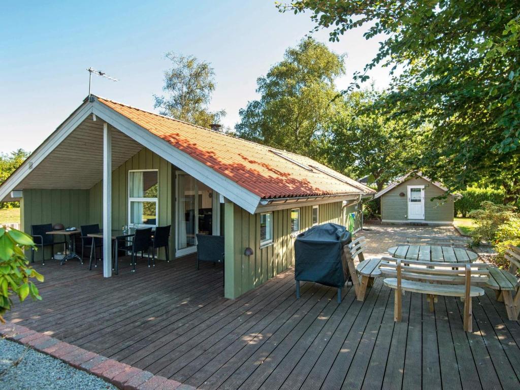 ein grünes Haus mit einem Tisch auf einer Terrasse in der Unterkunft One-Bedroom Holiday home in Hejls in Hejls