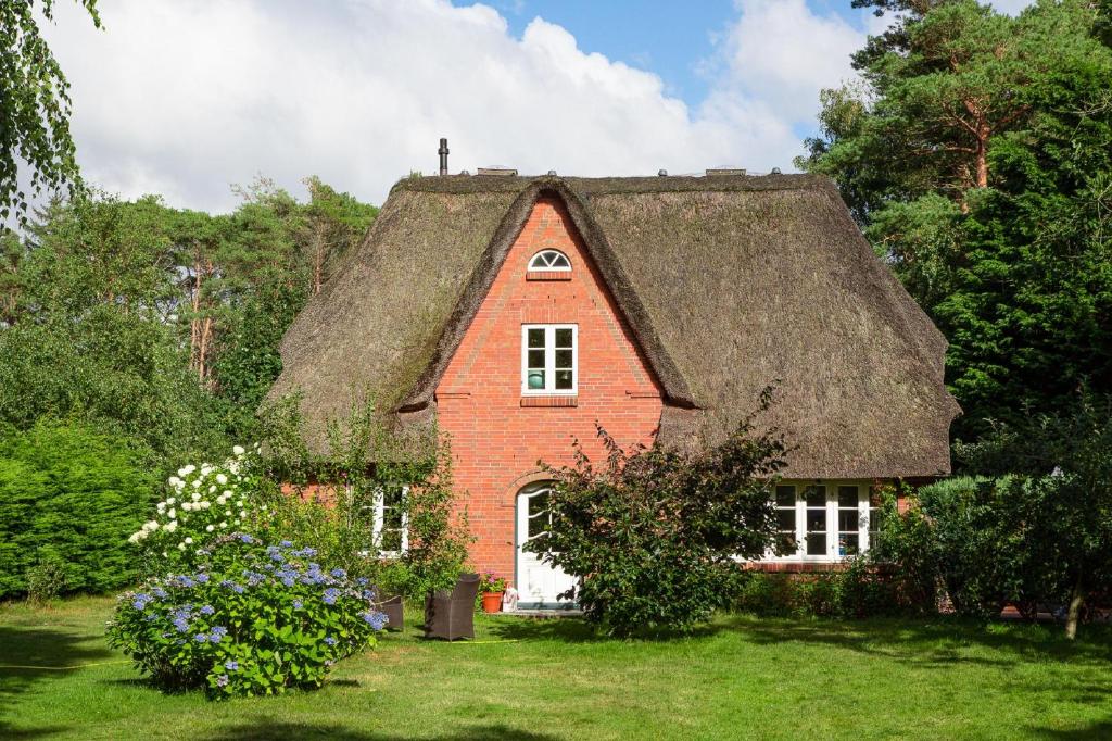 a red brick house with a thatched roof at Reetdachhaus Isemann in Nebel