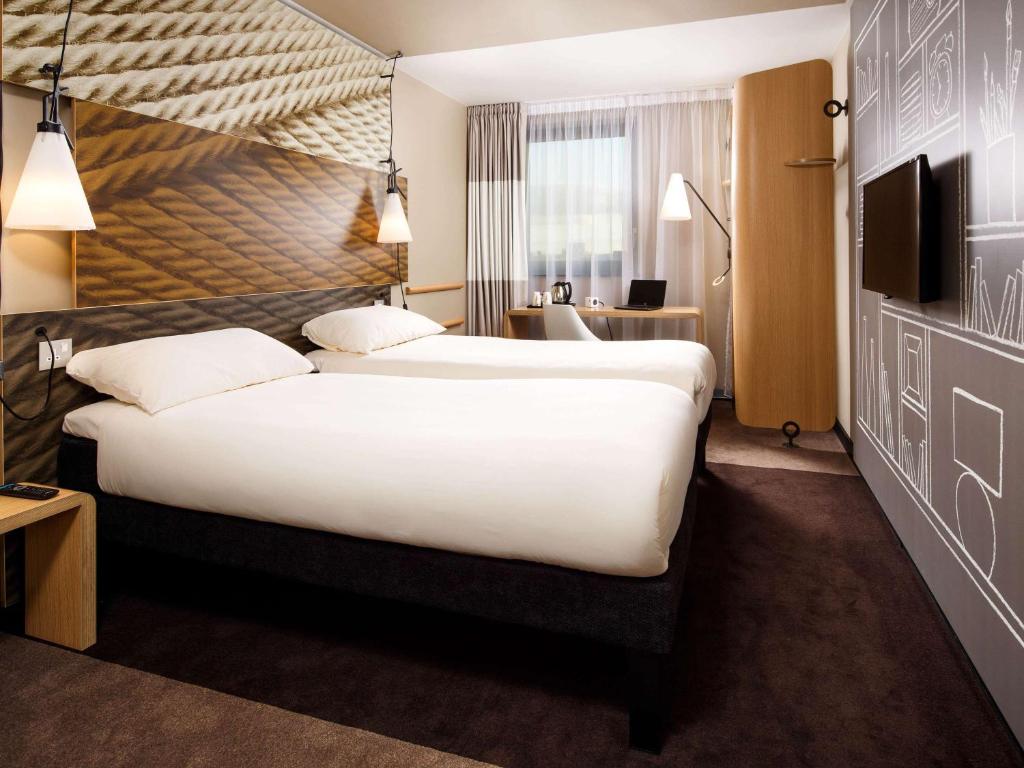 a hotel room with a large bed and a desk at ibis London City - Shoreditch in London