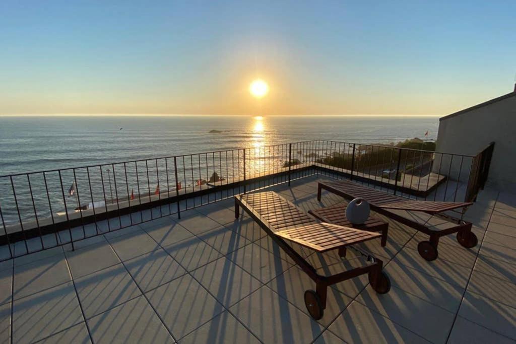 a balcony with a view of the ocean at sunset at BOUTIQUE Rentals- ATTICO Luxury Design-Ocean views in Porto