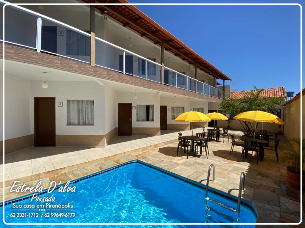 una casa con piscina, mesas y sombrillas en Estrela D Alva Pousada, en Pirenópolis