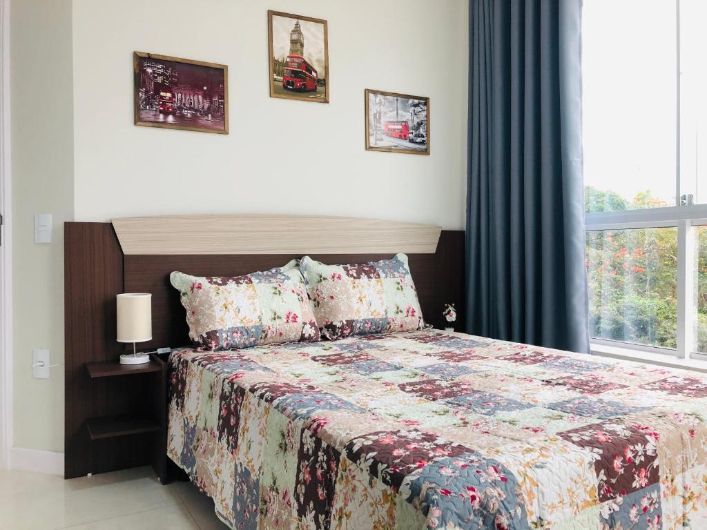 1 dormitorio con 1 cama con edredón y ventana en Residencial Spader - Bombinhas, en Bombinhas