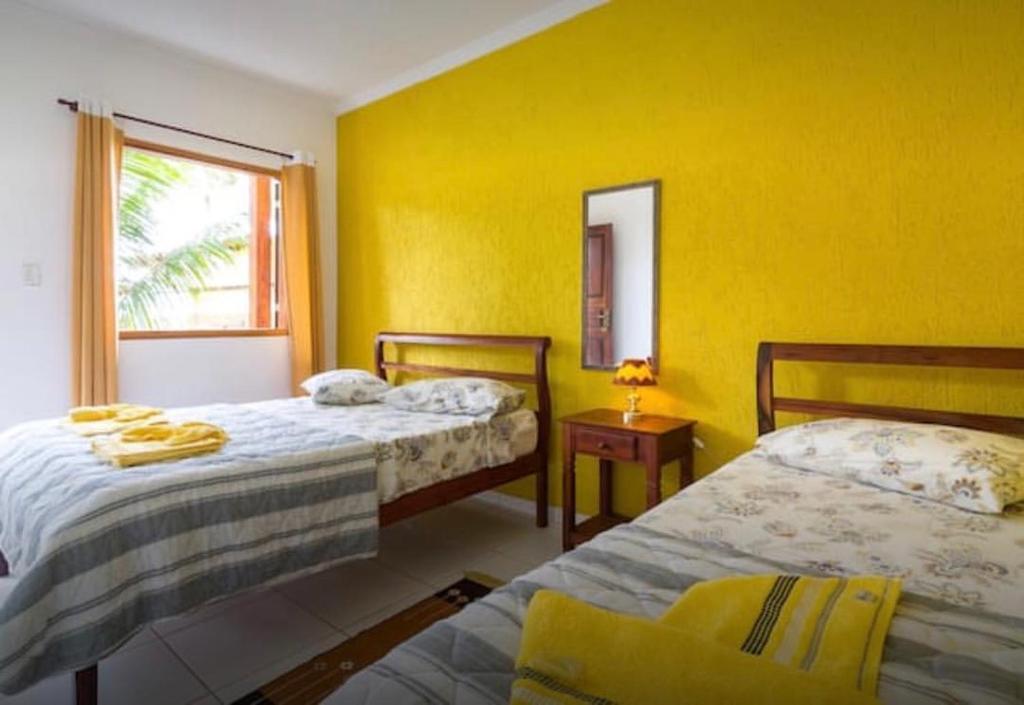 a yellow room with two beds and a window at Pouso Bom Retiro in Paraty