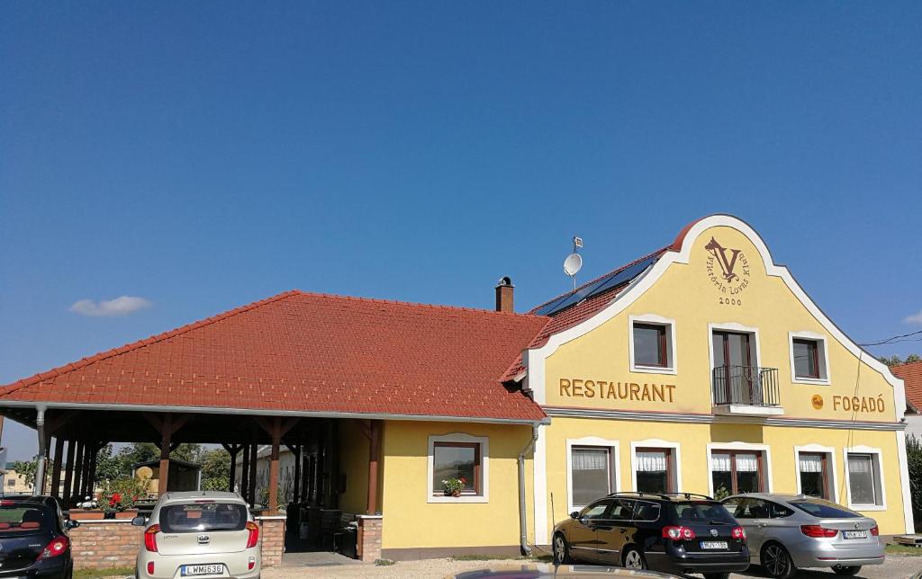 a restaurant with cars parked in front of it at Viktória Lovas Panzió in Győr