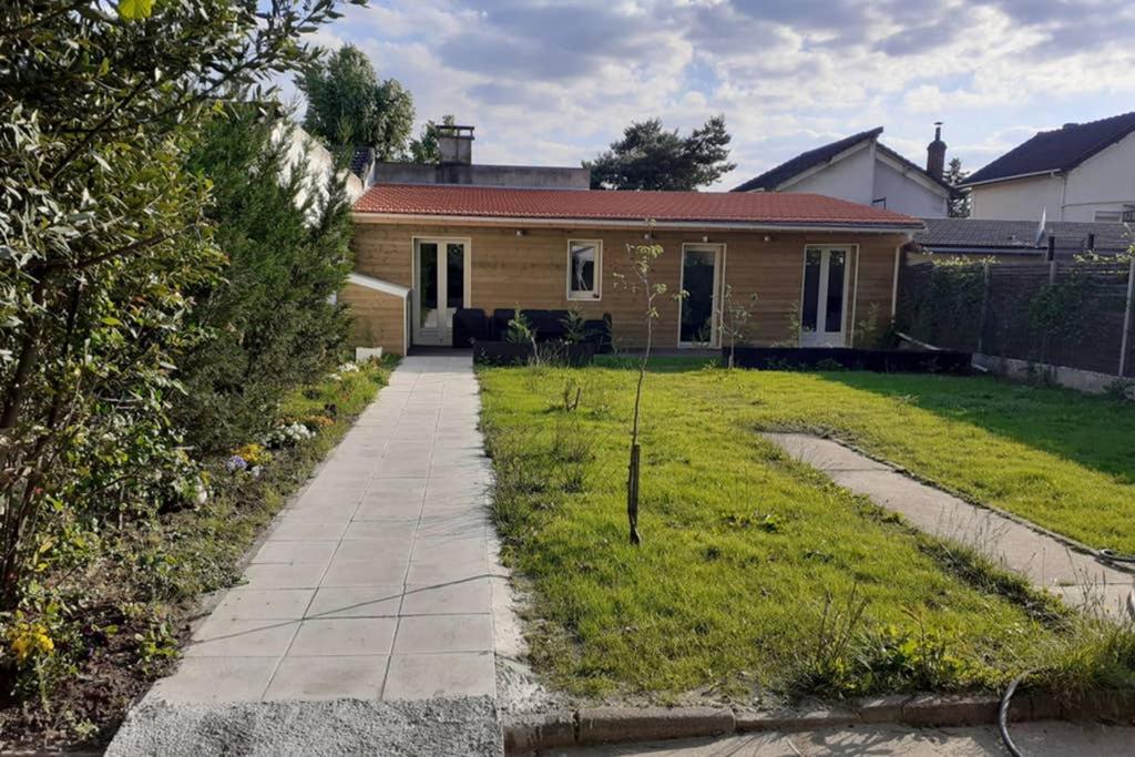 a house with a grass yard with a walkway at L'escapade parisienne in Aulnay-sous-Bois