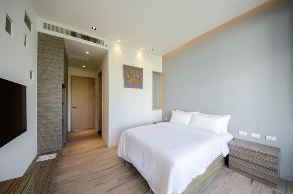 a bedroom with a white bed and a flat screen tv at 墾丁山風足跡 in Kenting