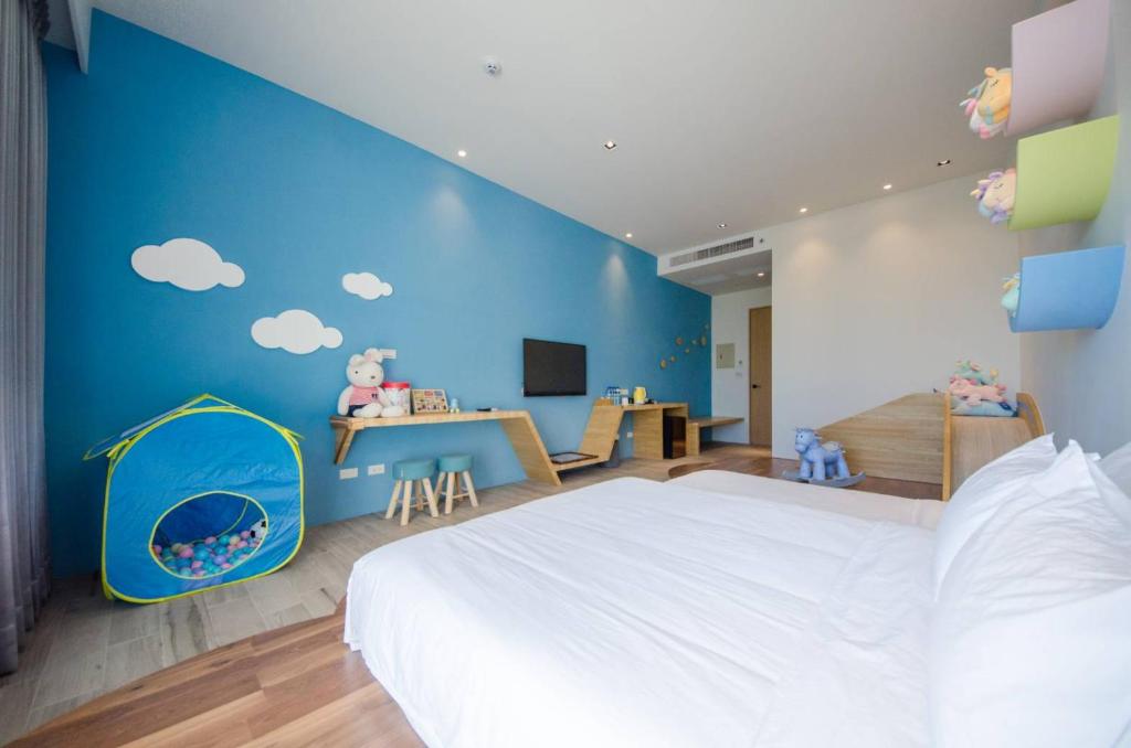 a bedroom with a white bed and a blue wall at 墾丁山風足跡 in Kenting