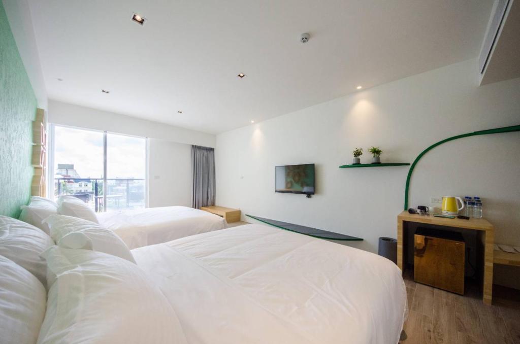 a hotel room with two beds and a window at 墾丁山風足跡 in Kenting