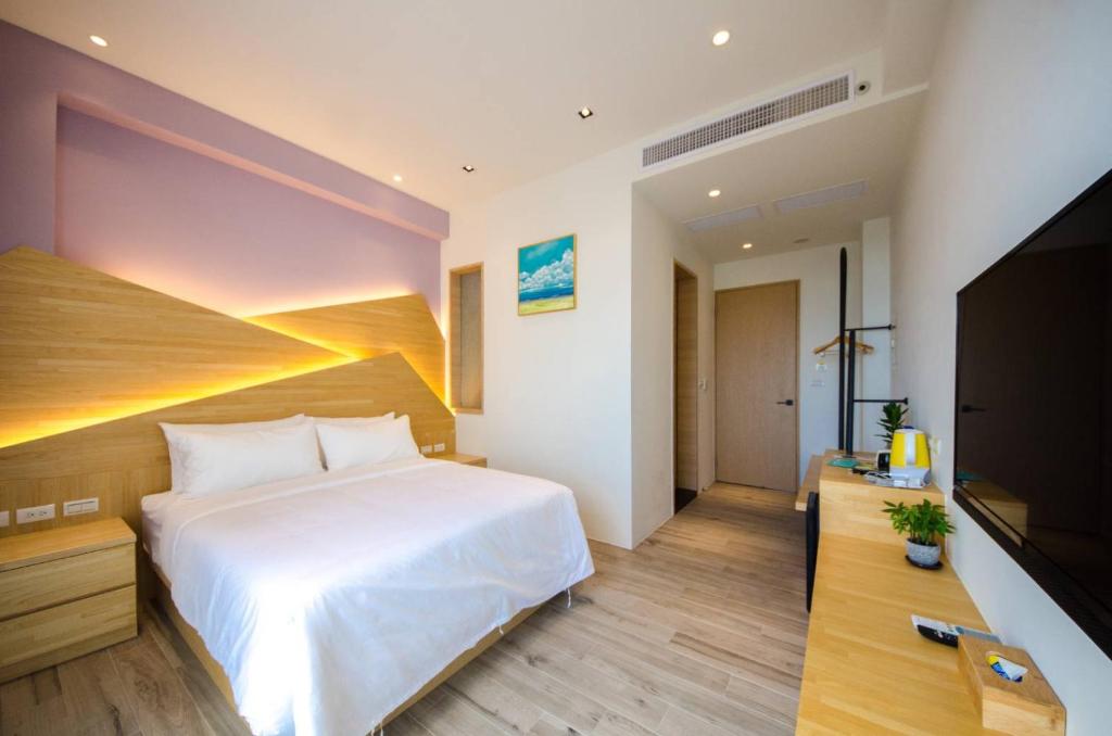 a bedroom with a white bed and a flat screen tv at 墾丁山風足跡 in Kenting