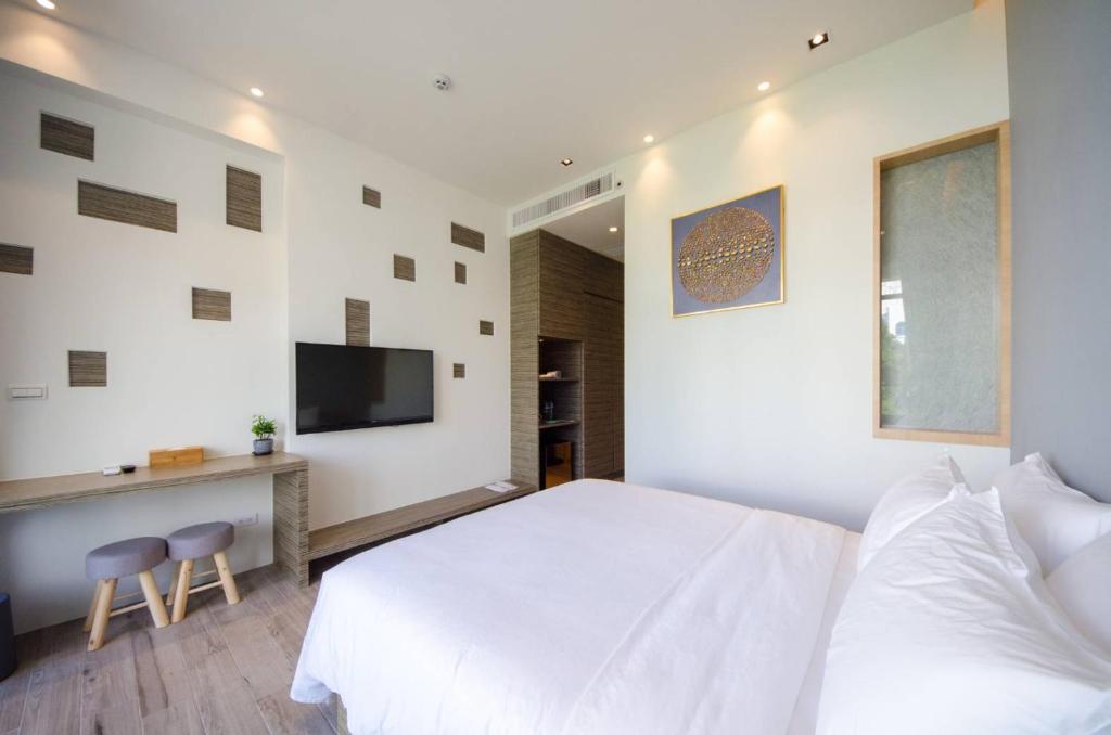 a bedroom with a white bed and a desk and a television at 墾丁山風足跡 in Kenting