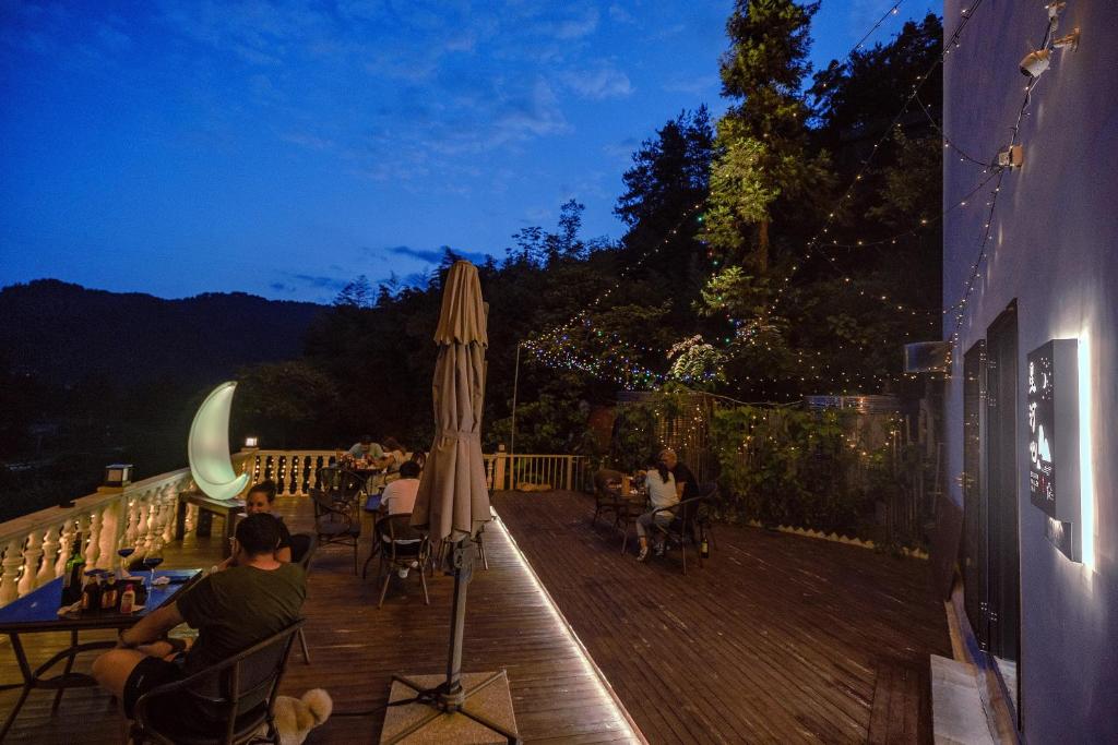 a wooden deck with people sitting on it at night at Whispering Mountains Boutique Hotel in Zhangjiajie