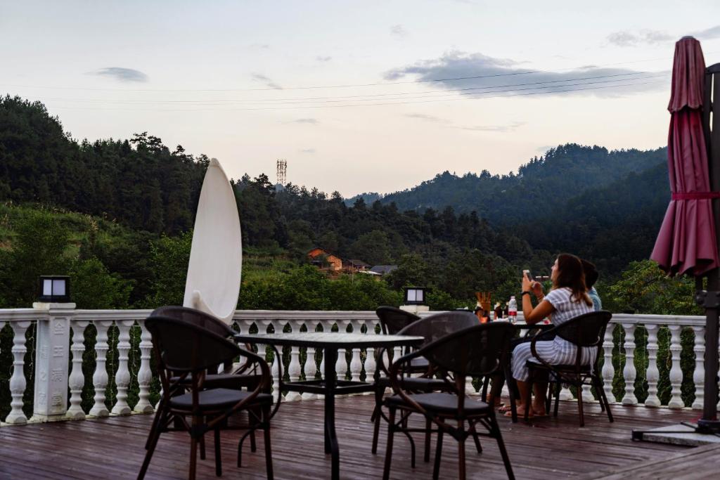 a woman sitting at a table on a deck at Whispering Mountains Boutique Hotel in Zhangjiajie