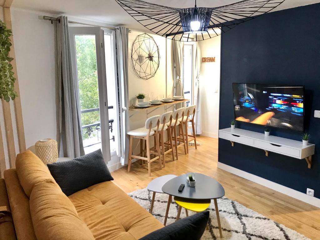 ein Wohnzimmer mit einem Sofa und einem TV in der Unterkunft Hullman Suite Apartment 4 People Between La Défense and Paris in Asnières-sur-Seine