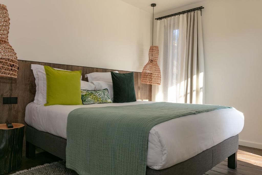 a bedroom with a large bed with green and white pillows at Domaine Santa Giulia Palace in Porto-Vecchio