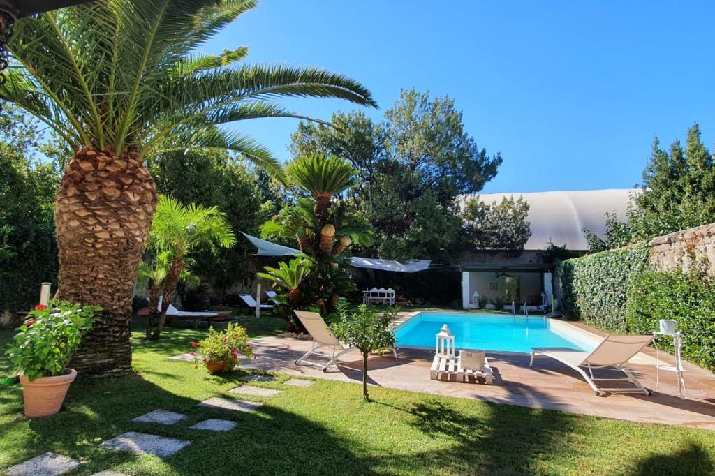 un jardín con piscina y palmeras en Casa Castagna en Caserta