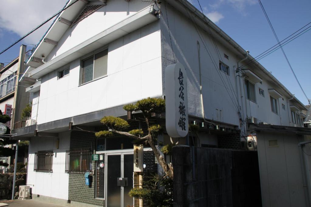 un edificio blanco con un cartel en el costado en Hase Ryokan, en Shingu