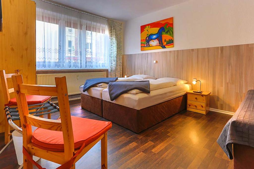 a bedroom with a bed and a table and a chair at H&H Apartment im Herzen der Stadt Nr 29-Henning mit Balkon in Greifswald