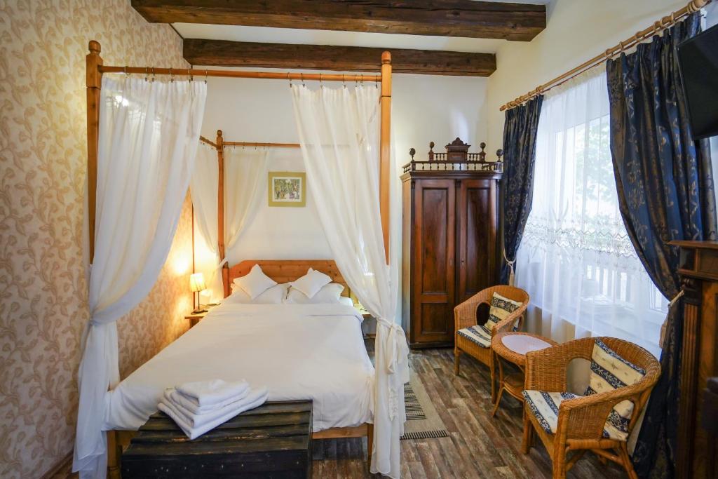 um quarto com uma cama de dossel e uma cadeira em Kron Studio Kalista em Braşov