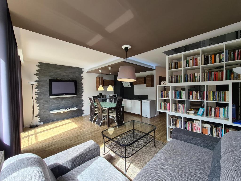 a living room with a couch and a table and books at Lux Apartment Modern in Polanica-Zdrój