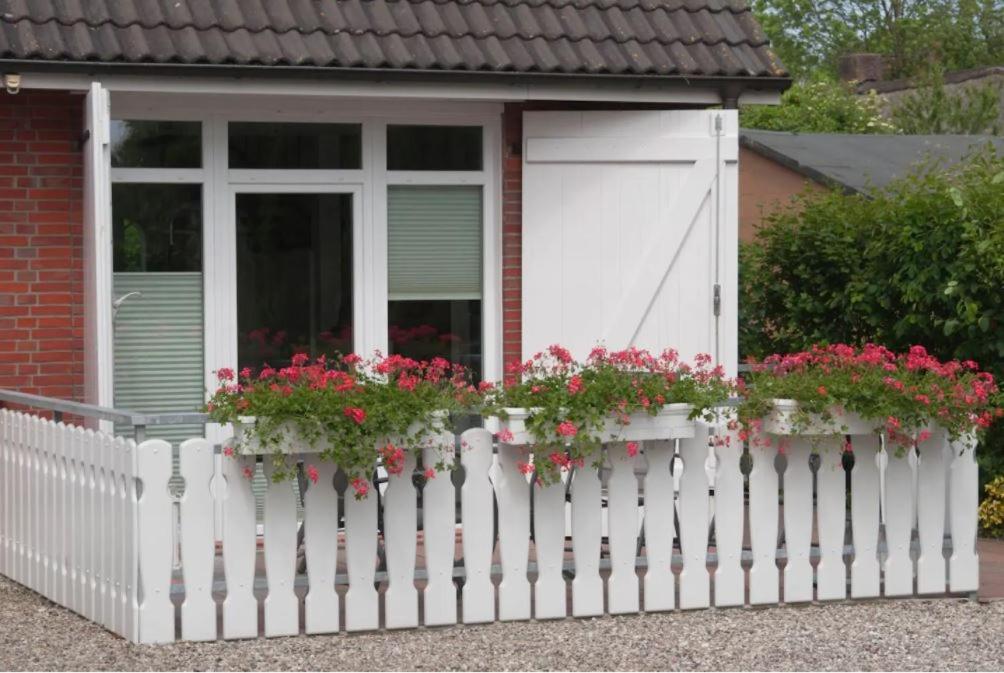 a white fence with flowers on it in front of a house at Ferien auf der Burg in Niebüll