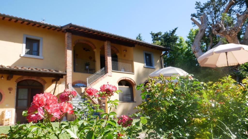 a house with flowers and an umbrella at Il Gelso in Montopoli in Val dʼArno