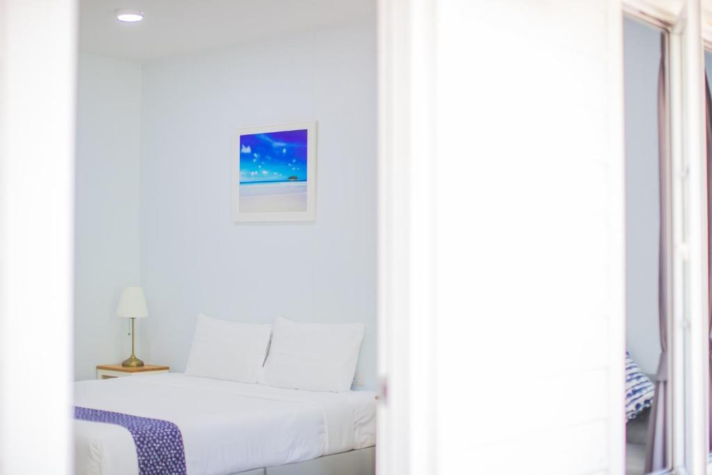 - une chambre blanche avec un lit et une fenêtre dans l'établissement Blue Shore Cottage, à Pak Meng