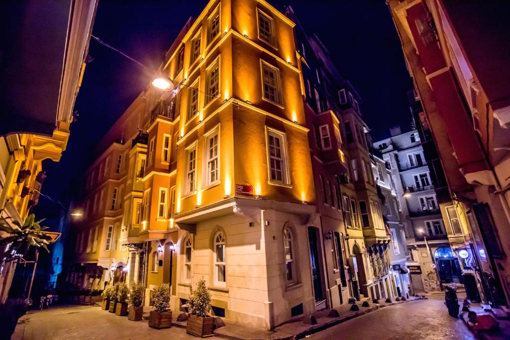 a tall yellow building with lights on it at night at Galata Door Hotel in Istanbul